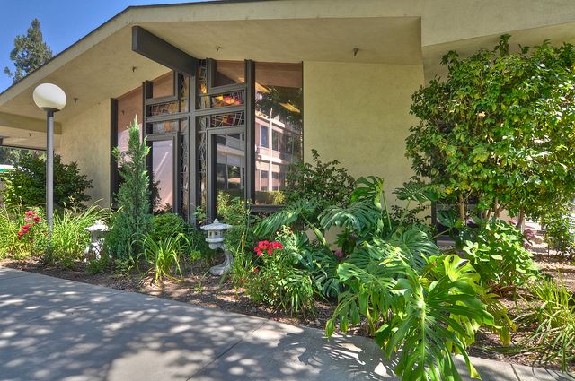 Senior living community, California Mission Inn - Rose Manor, featuring lush gardens, walkways, and villa-style housing.
