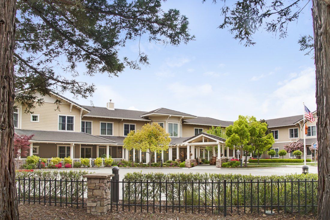 Senior living community, Sunrise of Rocklin, showcasing its architecture, outdoor yard with a bench and picket fence.