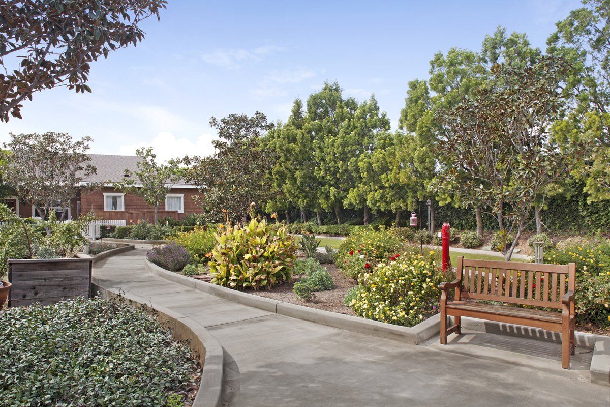 Senior living community Ivy Park at Tustin, featuring lush gardens, park benches, and urban housing.
