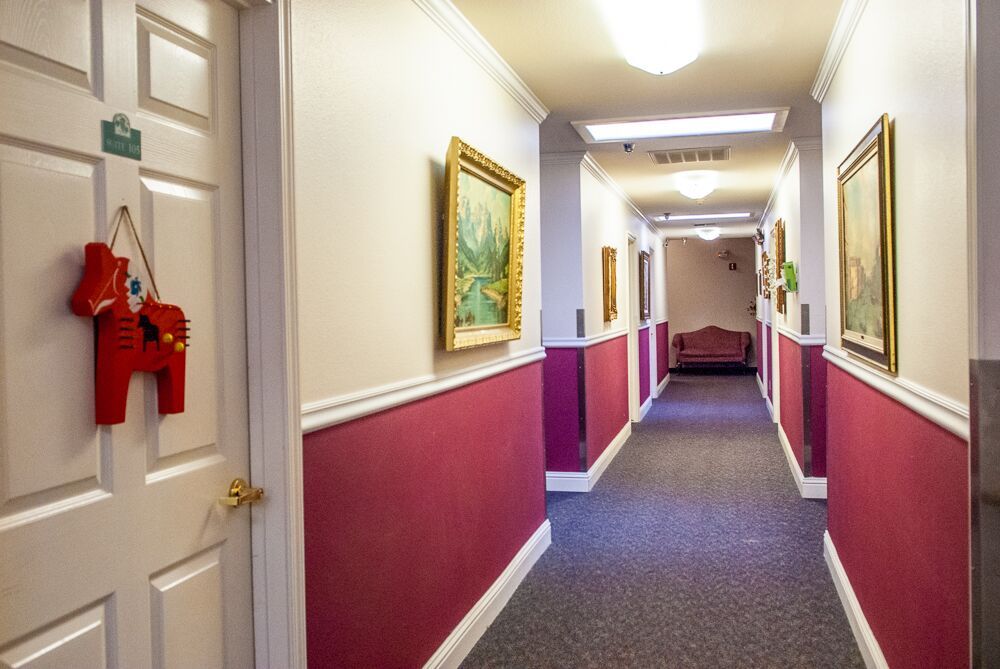 Indoor hallway of The Harvest at Fowler senior living community, featuring art, furniture, and architecture.