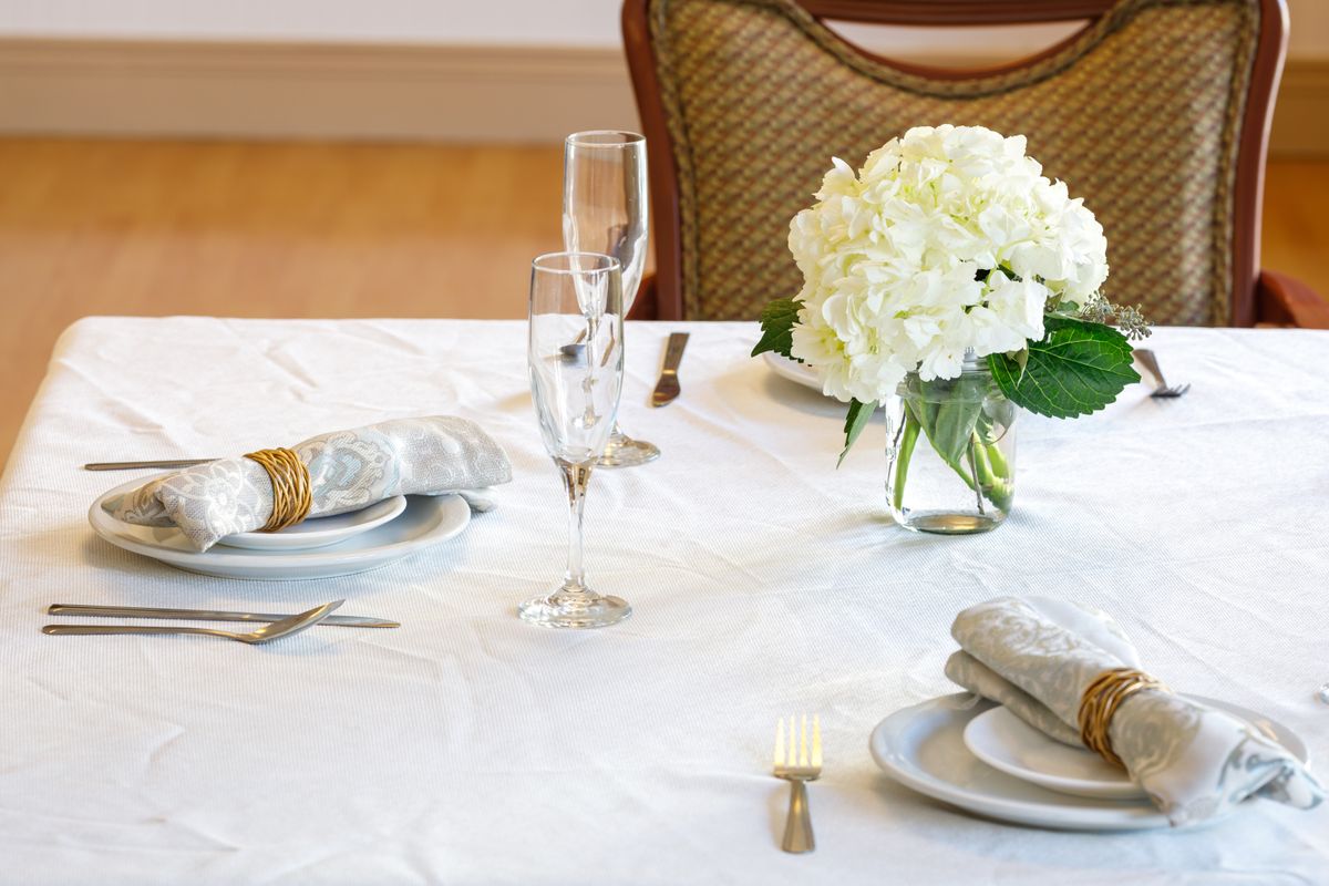 Floral centerpiece on a dining table with cutlery and linen at Ocean Pointe Senior Living.