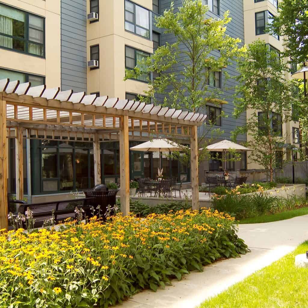 Senior living community JFK Apartments featuring urban architecture, garden, and patio.