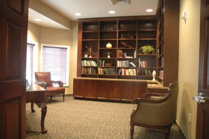 Senior resident reading in a cozy, wood-furnished library at Streamside Assisted Living community.