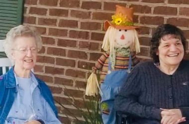 Senior woman at Providence Place of Mt. Juliet, enjoying winter outdoors with a snowman and potted plants.