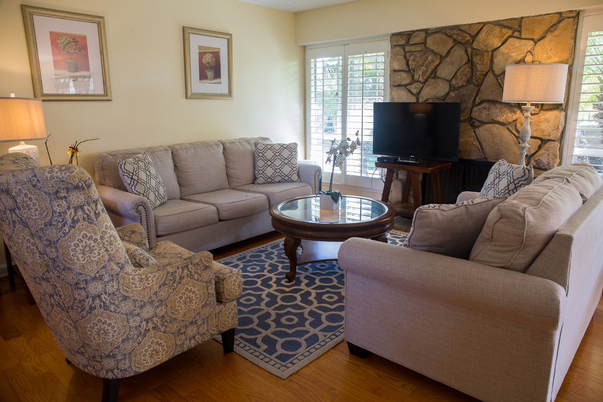 Senior living room interior at Ocean Breeze Estates, featuring modern decor, electronics, and fireplace.