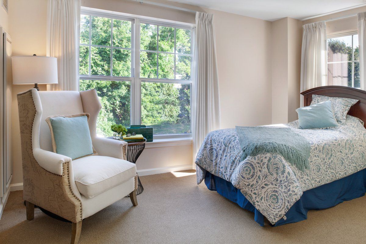 Bedroom interior at Sunrise of Wayland senior living community with bed, furniture, and bay window.