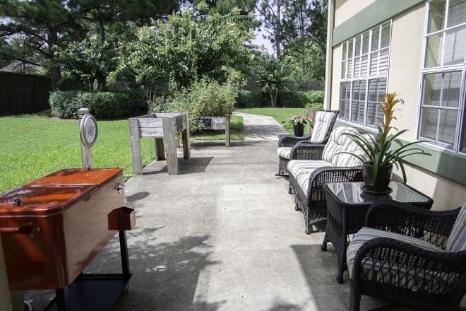 Senior living community, Brookdale Dowlen Oaks, featuring outdoor patio with furniture and lush greenery.