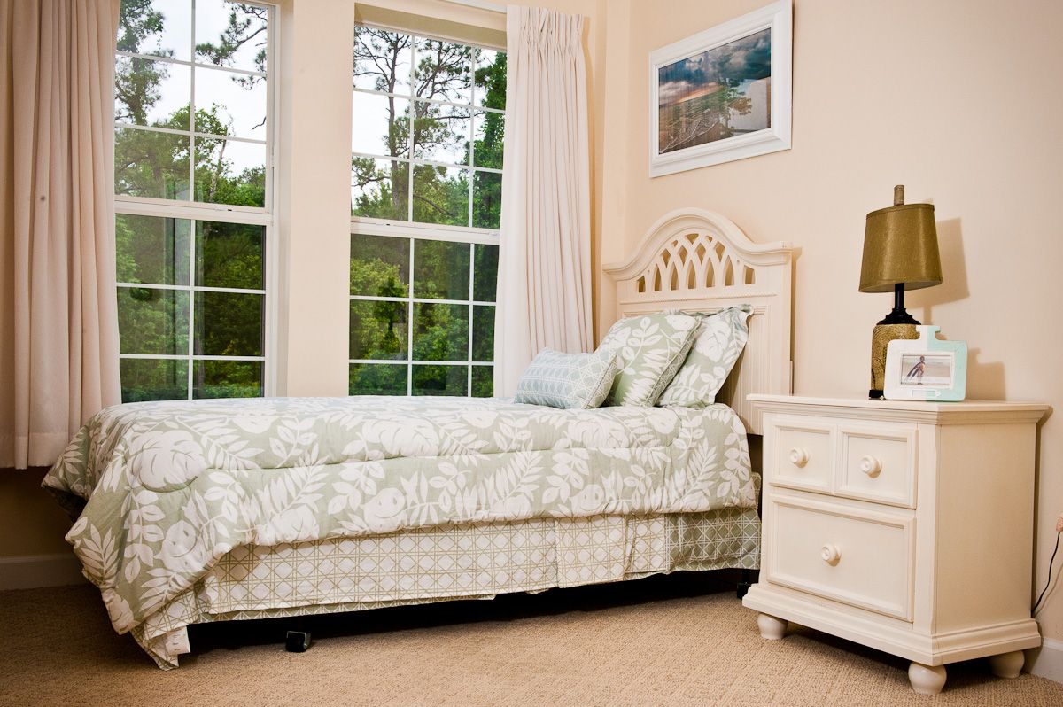 Interior design of a bedroom at Spring Hills in Morristown, featuring a bed, table lamp, and window.