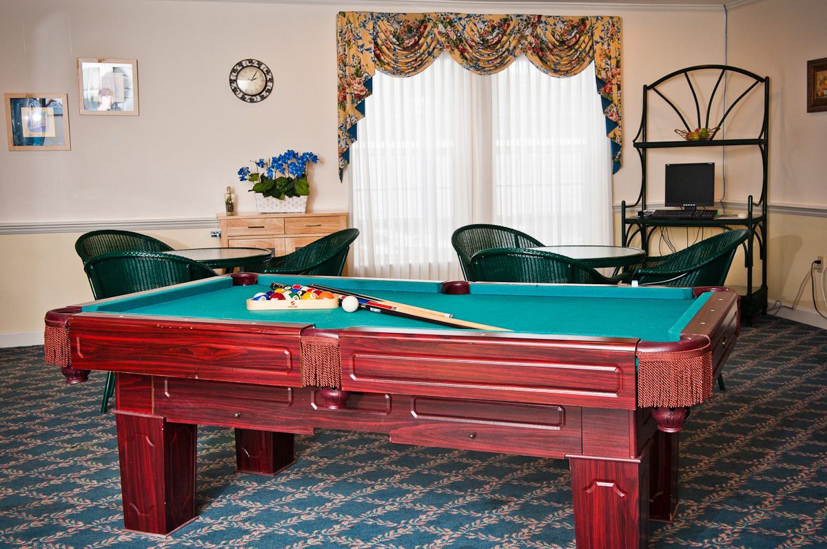 Seniors enjoying billiards in the game room with computer and TV amenities at Spring Hills Morristown.