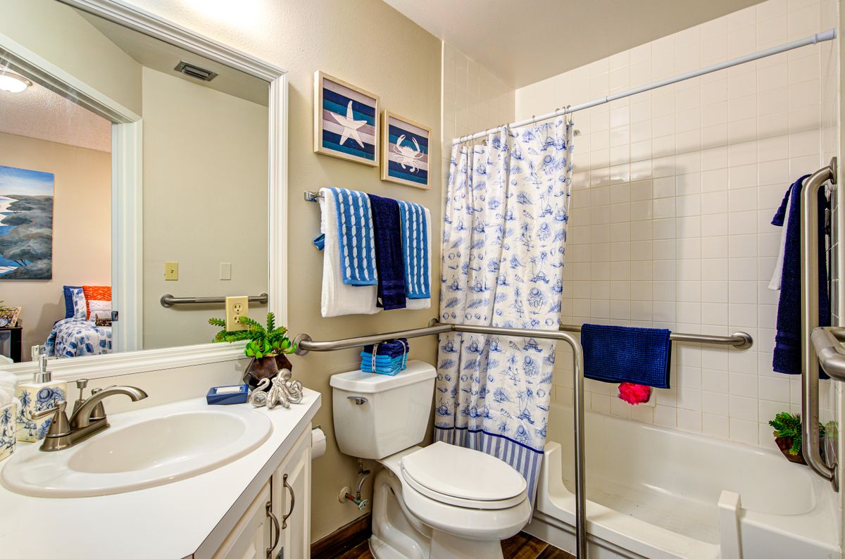 Senior resident in Pacifica Senior Living Sunrise community bathroom with tub, sink, and indoor plants.