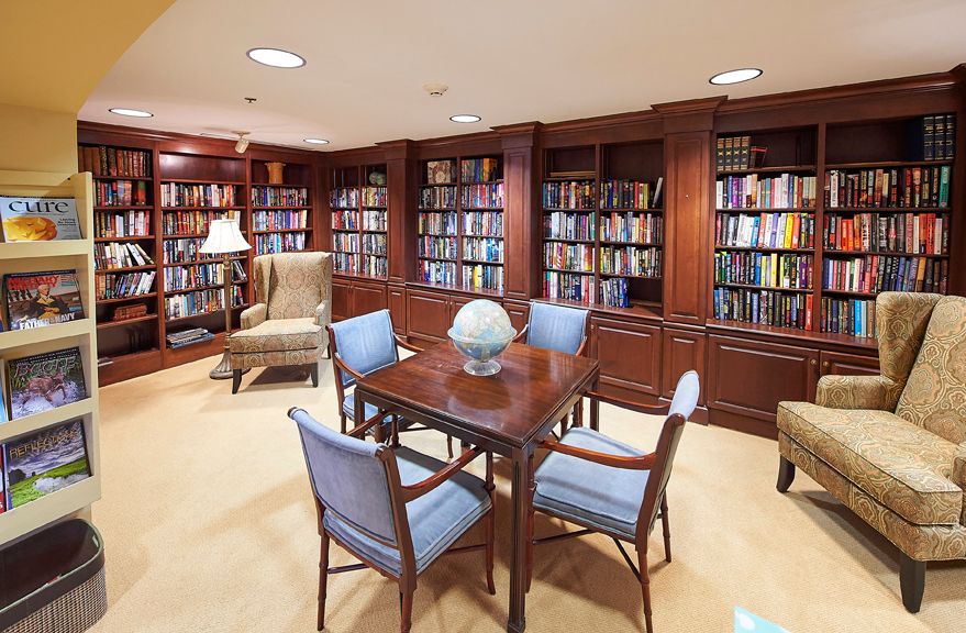 Senior living community library at Redstone Village with books, furniture, and dining area.