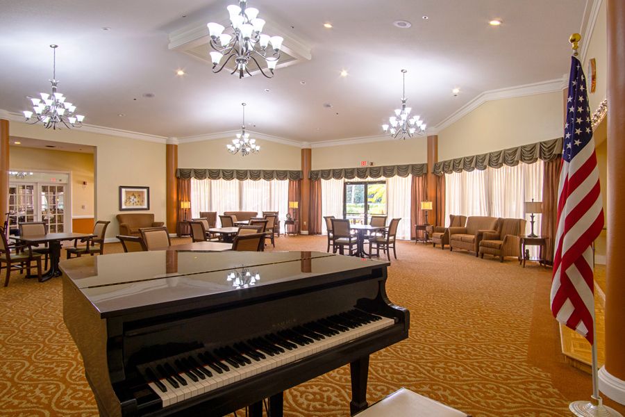 Interior view of Elison Independent Living in Lake Worth, featuring grand piano, chandelier, and elegant decor.