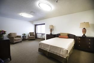 Bedroom interior at Sunny Ridge Senior Living with comfortable furniture and warm lighting.