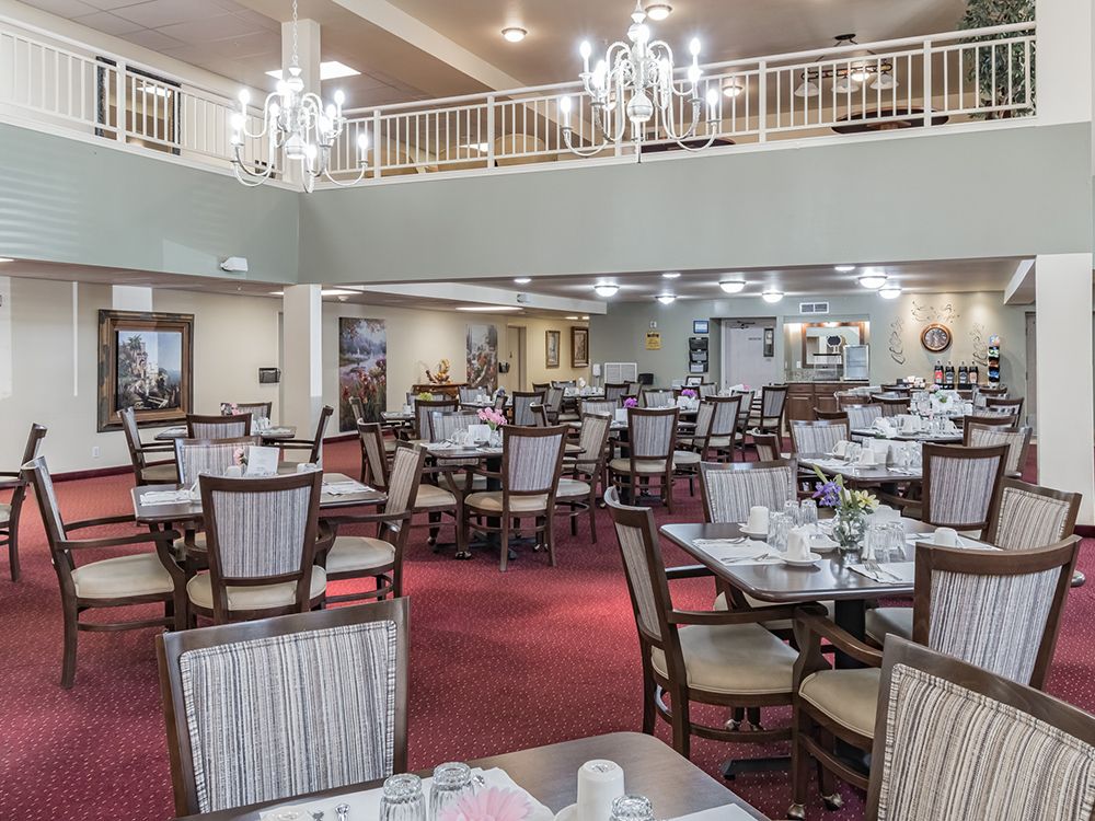 Indoor view of Gardens At Arkanshire senior living community featuring dining room, furniture, and chandelier.