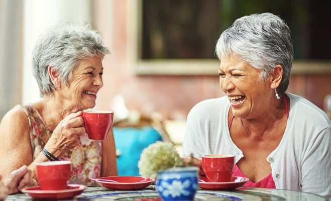 Happy senior laughing with a coffee cup at Artisan At Hudson senior living community.