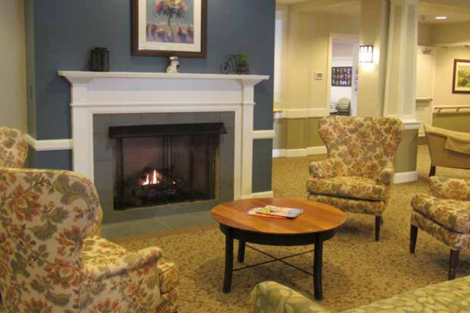 Senior living room at Alexian Village of Elk Grove featuring a fireplace, cozy furniture, and home decor.