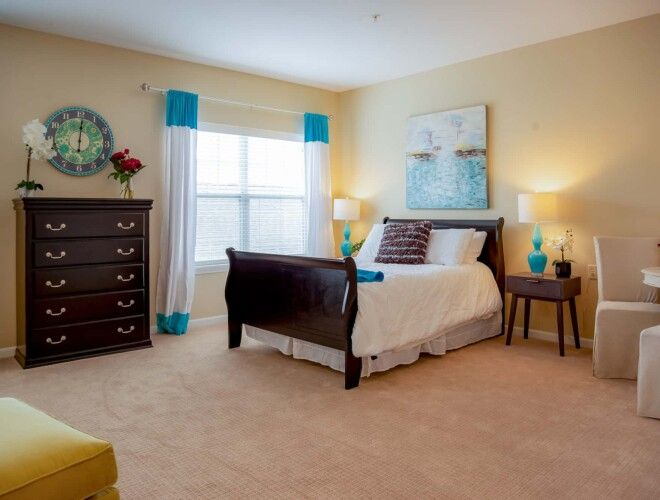 Senior living room at Deerfield with furniture, home decor, bed, cabinet, and lamp.
