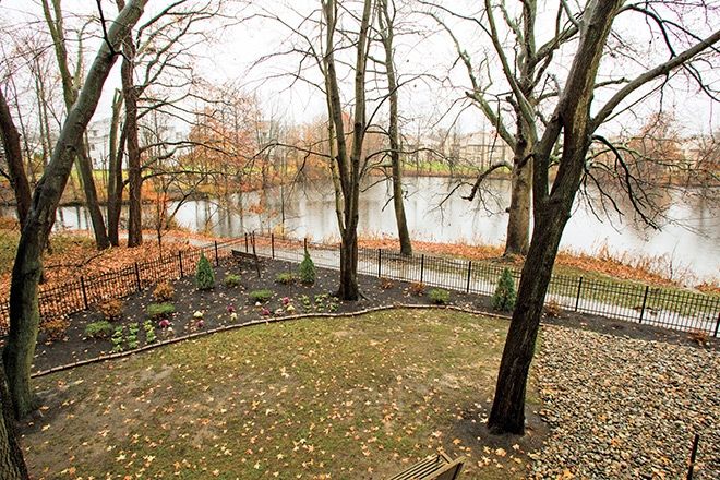Scenic view of Brookdale Echelon Lake senior living community with lush trees, pond, and park bench.