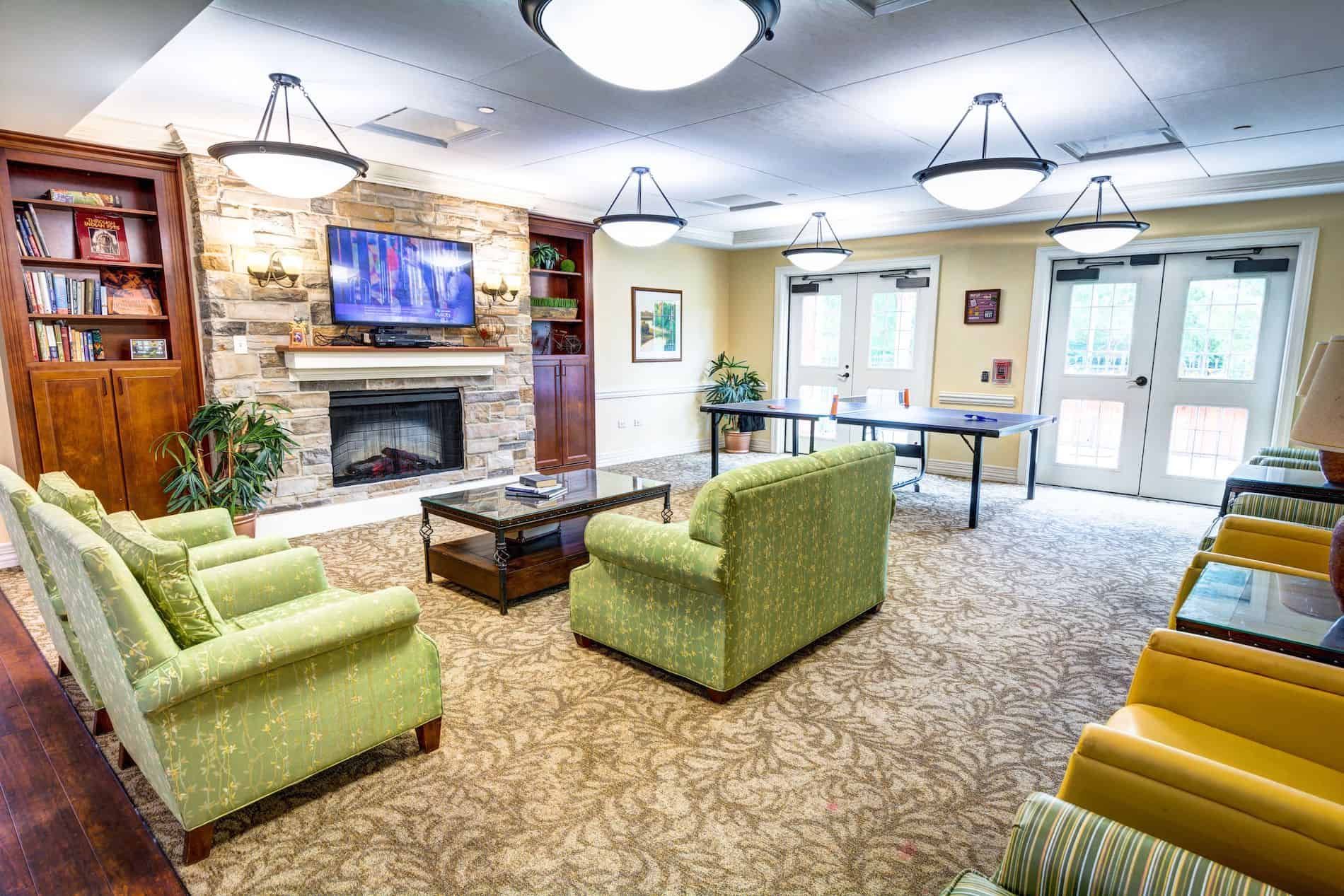 Senior enjoying a cozy living room with modern decor and fireplace at The Auberge At Naperville.