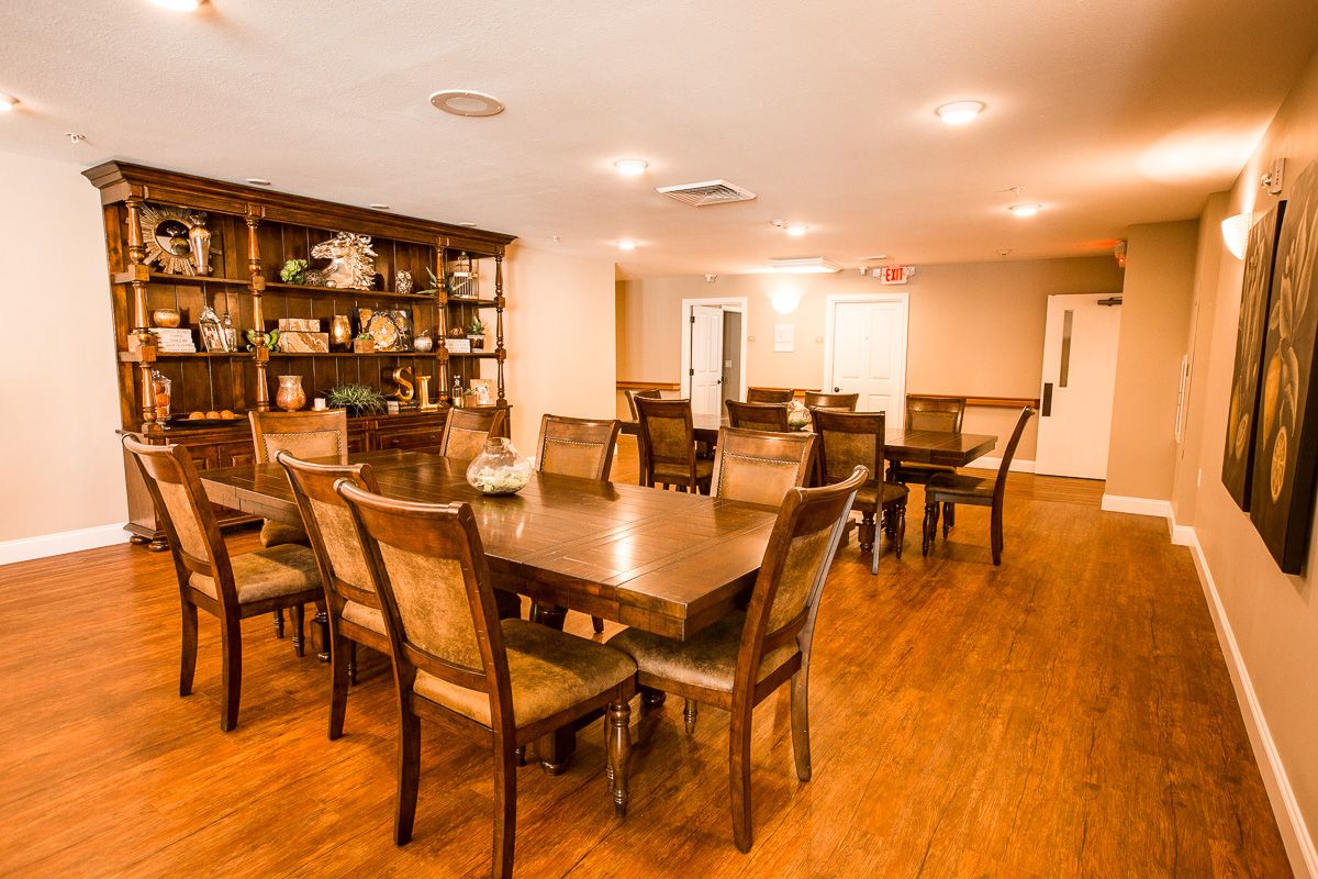 Interior view of Signature Lifestyles II senior living community featuring hardwood flooring, stained wood furniture in dining and living room areas.