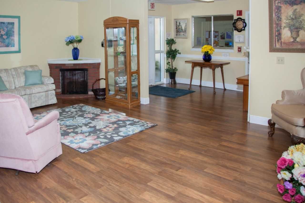 Hardwood floored living room with furniture and fireplace in Pleasant Grove Manor senior community.