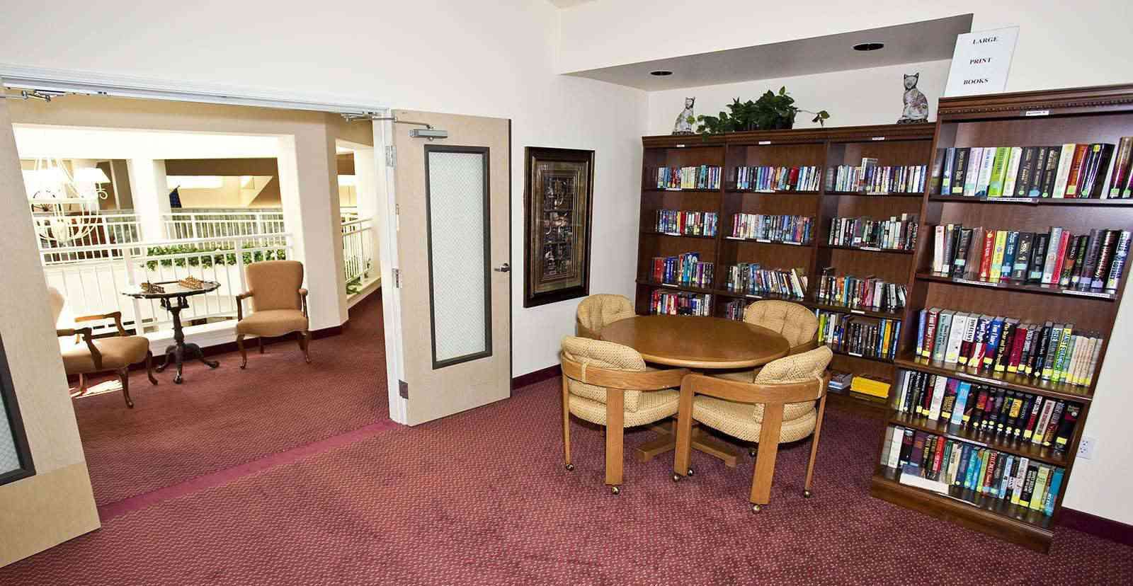 Seniors reading in the library at Solstice Senior Living At Apple Valley with cozy furniture.