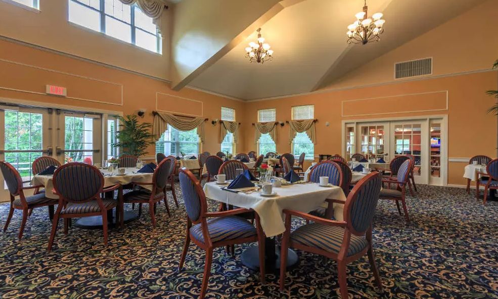Seniors enjoying in the dining room of All American Assisted Living at Raynham with elegant furniture.