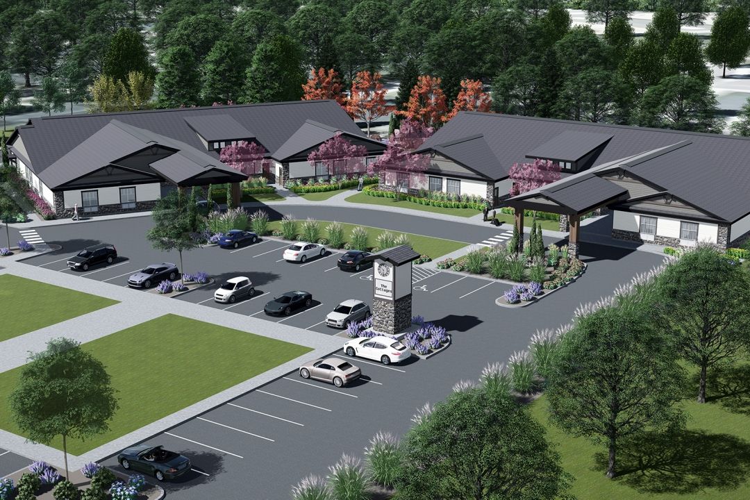 Aerial view of The Cottages at Lochsa Falls senior living community with cars and buildings.