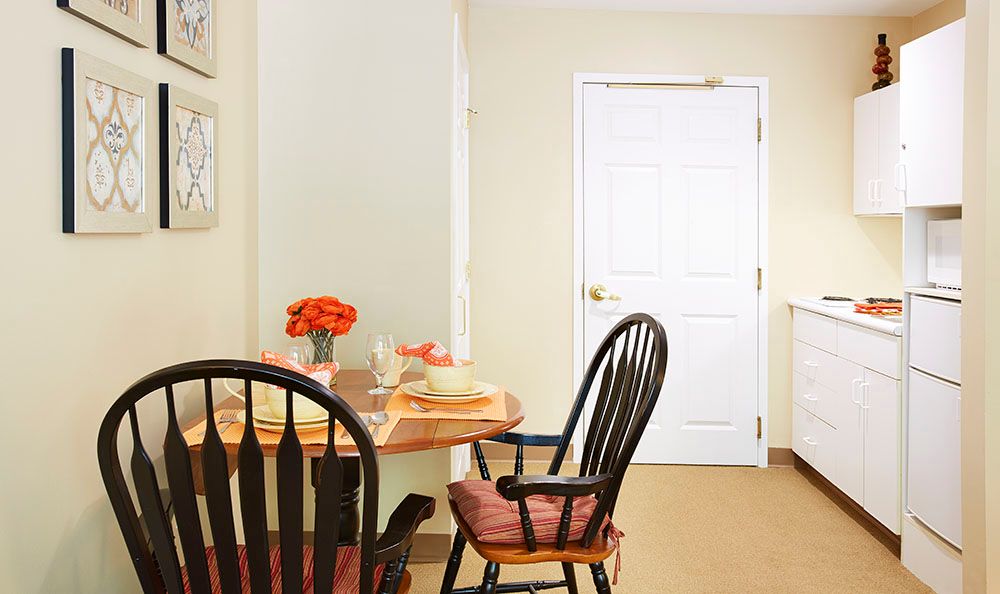 Senior living community interior at Tatnuck Park, Worcester featuring dining room, kitchen, and art decor.
