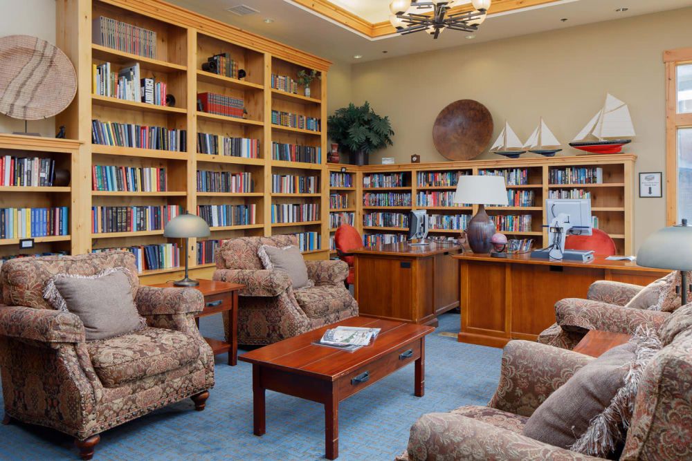 Senior living community library at Touchmark At Meadow Lake Village with furniture and electronics.