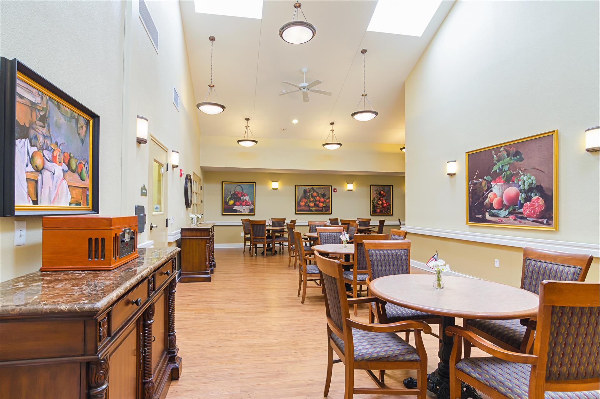 Interior view of The Gardens At Barry Road Assisted Living, featuring dining area with wooden furniture and art.