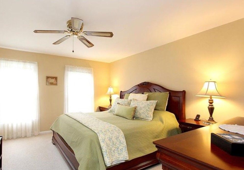 Quality Comfort Care senior living community bedroom with lamp, ceiling fan, and decor.