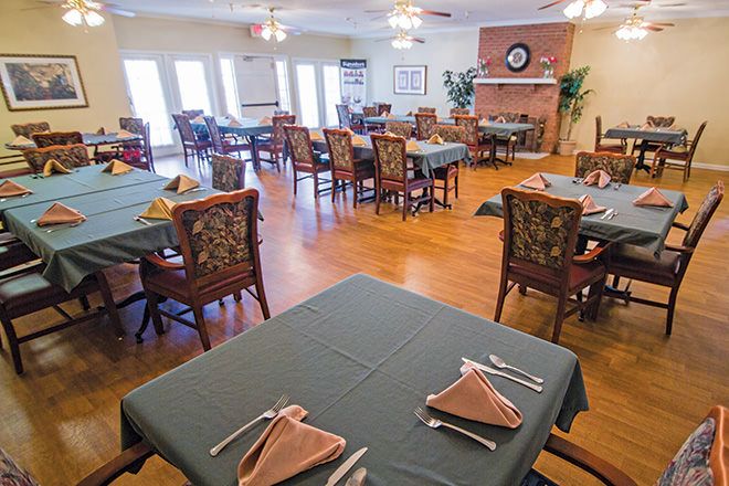 Senior living community at Monarch Place featuring a well-furnished dining room with hardwood decor.
