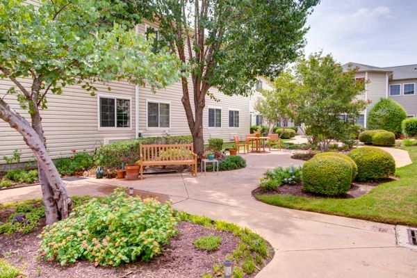 Senior living community, Court At Round Rock, featuring lush gardens, outdoor furniture, and modern architecture.