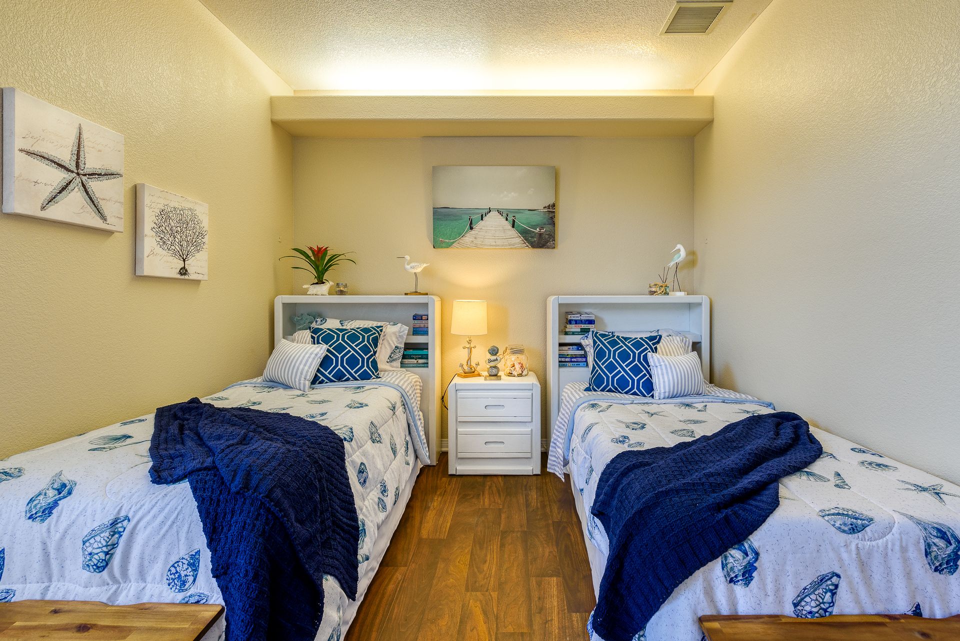 Interior view of a furnished bedroom at Pacifica Senior Living Newport Mesa with hardwood flooring.