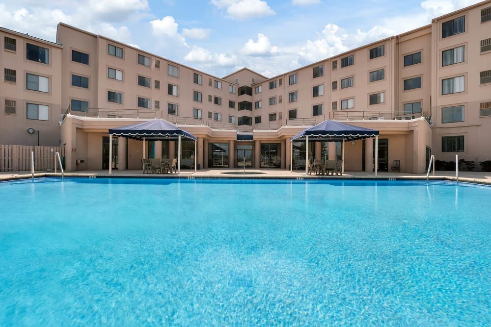 Spring Haven senior living community featuring a swimming pool, outdoor furniture, and hotel-style architecture.