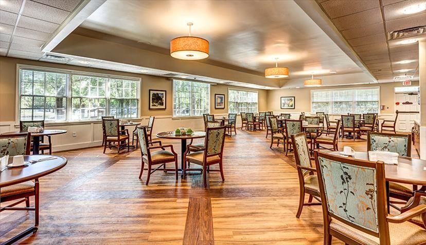 Interior view of Sentara Village at Virginia Beach featuring dining area with wooden furniture and art.