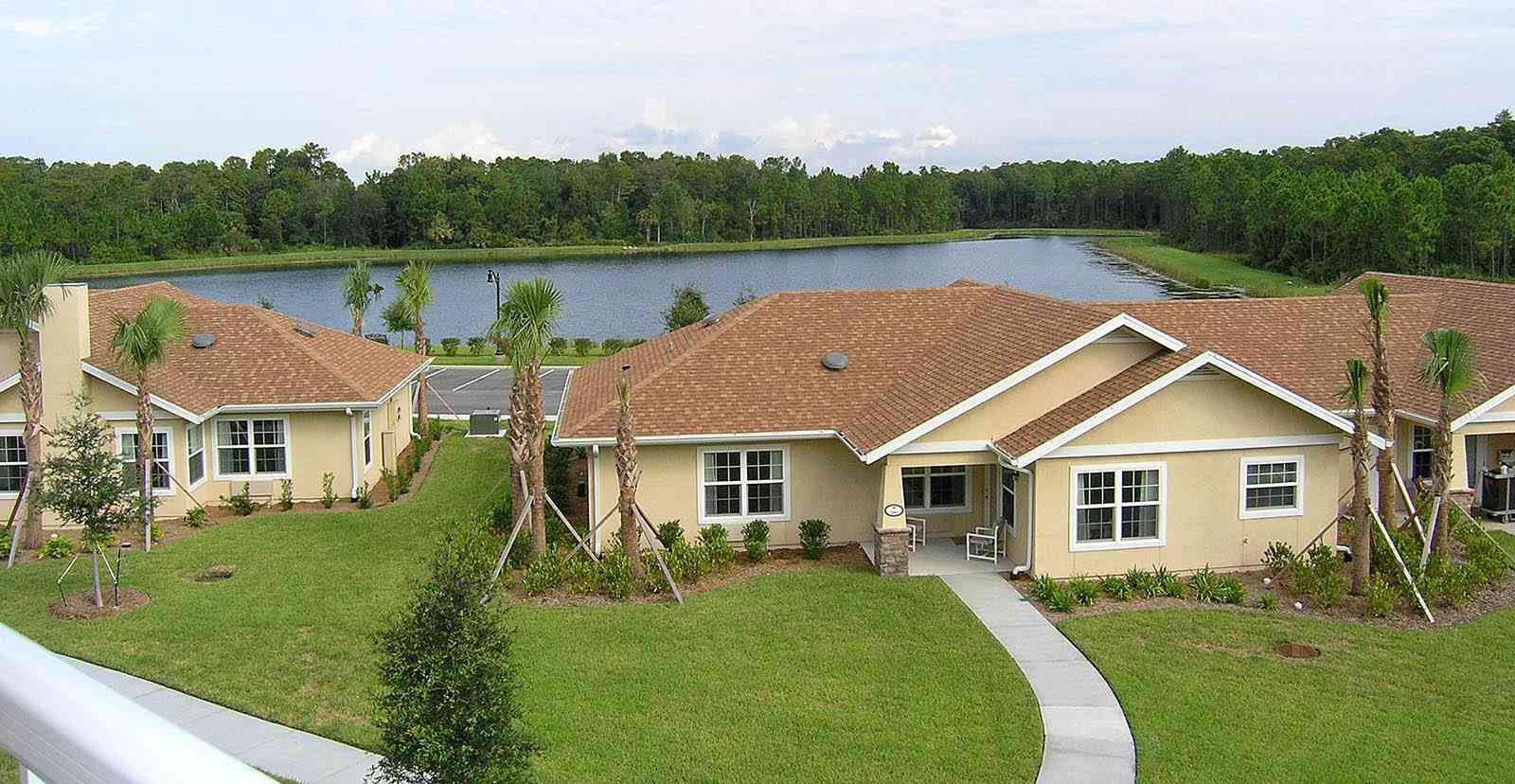 Senior living community in Las Palmas with scenic waterfront, lush grass, and plant life.