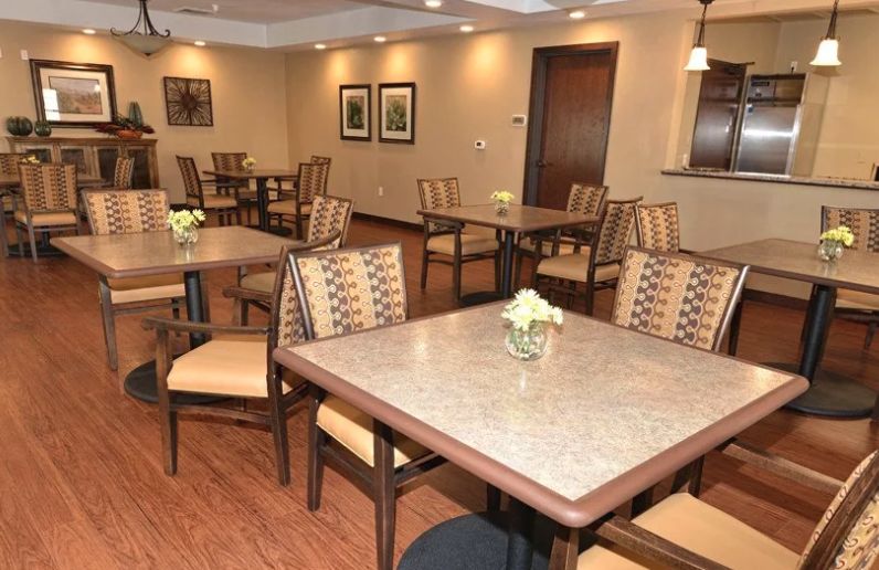 Interior view of Caliche Senior Living community featuring a well-designed dining room with wooden furniture.
