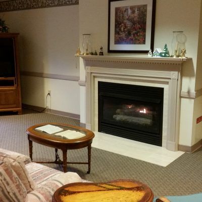 Interior view of Terraces At Parke Place senior living community featuring a cozy fireplace, elegant furniture, and art.