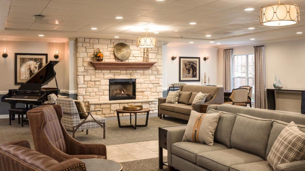 Interior view of Belmont Village Senior Living Buffalo Grove featuring a piano, fireplace, and cozy furniture.