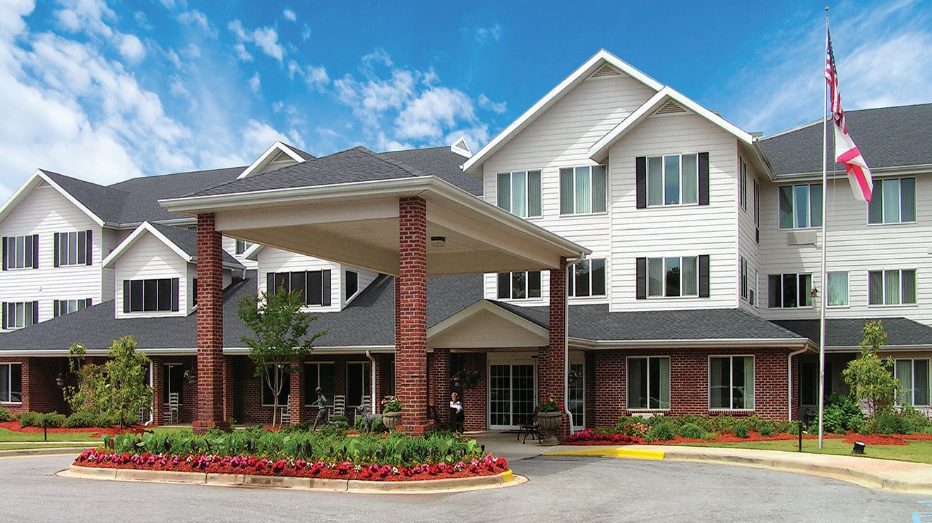 Senior living community in Rocky Ridge with lush grass, modern architecture, and residents.