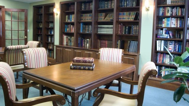 Senior living community library at Lincolnwood Place with bookcases, tables, and chairs.