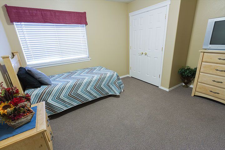 Interior view of Ashley Manor Cedar senior living community featuring a furnished bedroom with modern decor and electronics.