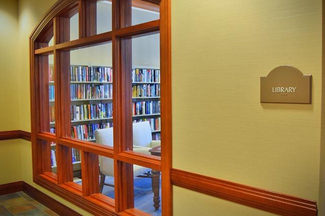Interior view of Villa St. Benedict senior living community library with bookcases and chairs.