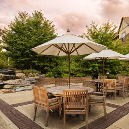 Senior living community, Danberry At Inverness, featuring patio dining area with furniture and lush greenery.