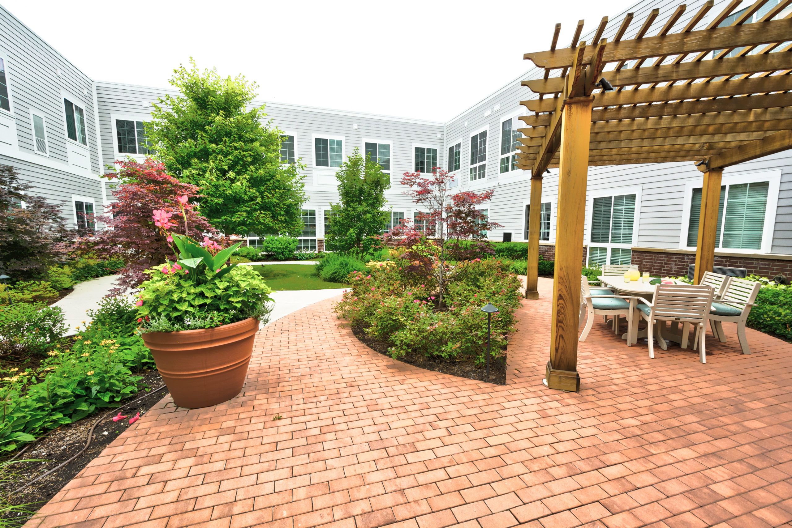 Palos Heights Senior Living community featuring lush gardens, patio seating, and beautiful architecture.