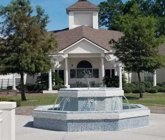 Mathison Retirement Community featuring a villa-style building, lush grass, plants, a fountain, and outdoor hot tub.