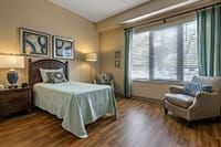 Interior view of a well-designed bedroom with wooden flooring at Brookdale Lisle Senior Living Community.