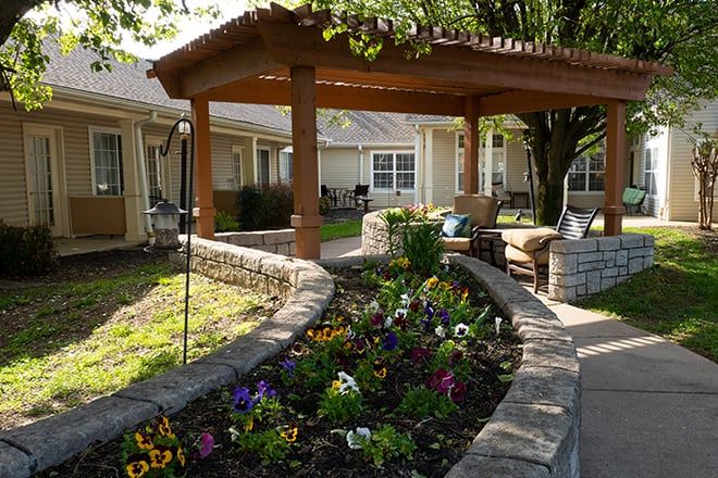 Brookdale Gallatin senior living community featuring a lush garden, patio furniture, and housing architecture.